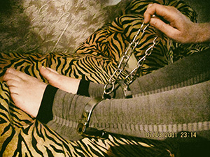 Dolly in leggings plays with handcuffs, shackles
